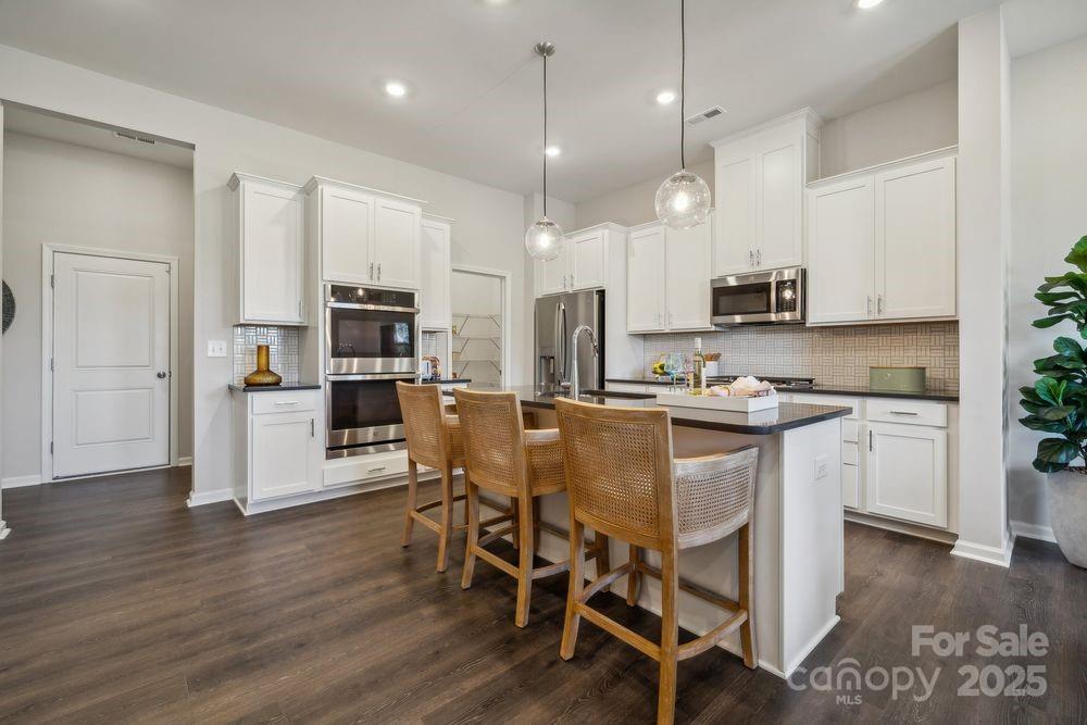 8661 Miles Gap Road Indian Land, SC 29707 - Photo 6 of 31 a kitchen with stainless steel appliances granite countertop a refrigerator a stove top oven a sink dishwasher and white cabinets with wooden floor