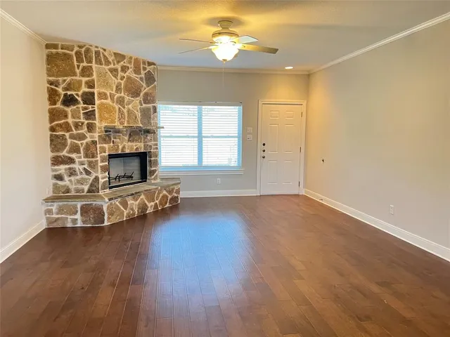 an empty room with windows fireplace and wooden floor