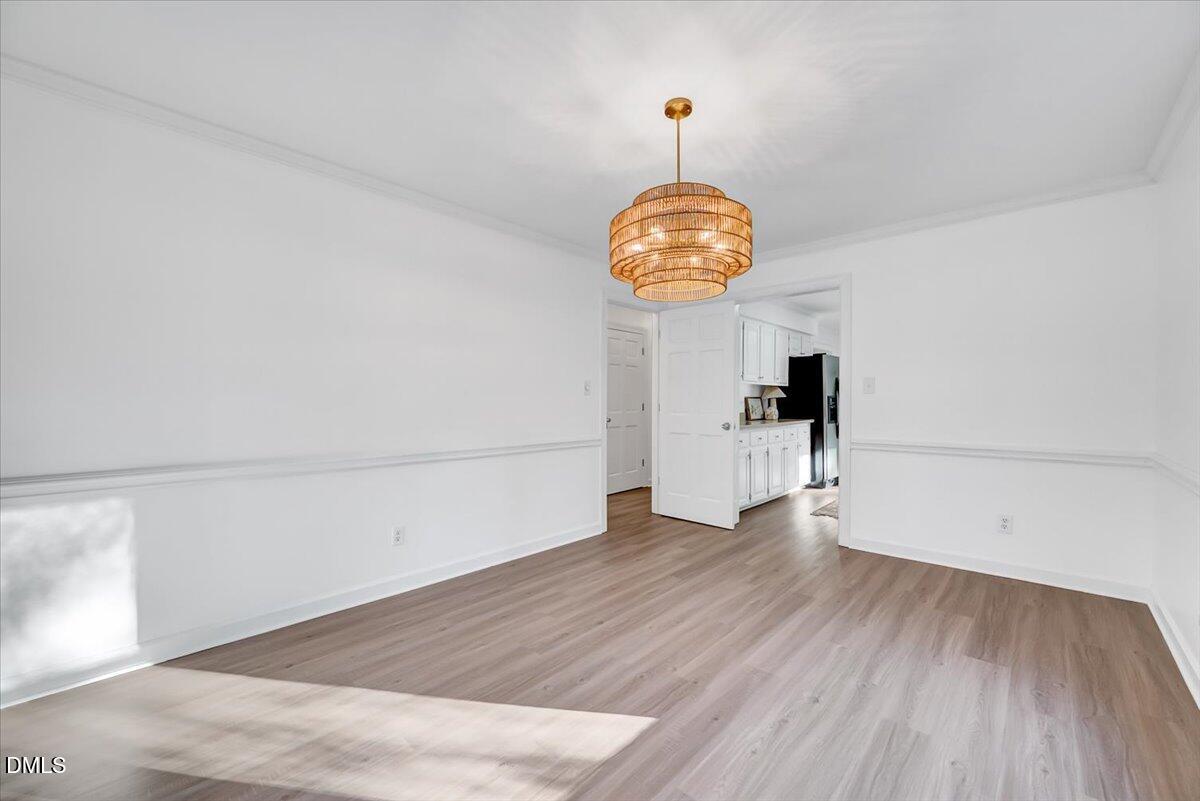 1208 Turner Farms Road Garner, NC 27529 - Photo 19 of 38 an empty room with wooden floor and chandelier