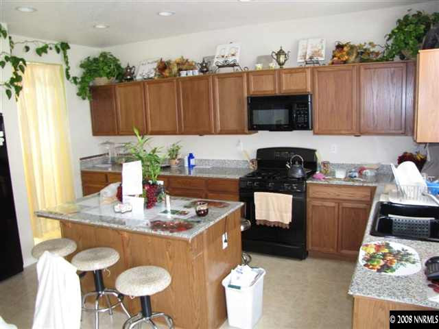 8917 Mahon Drive Reno, NV 89506 - Photo 5 of 9 a kitchen with a stove a sink and a dining table