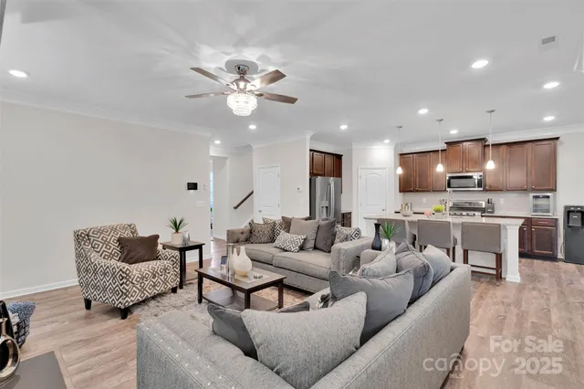 a open kitchen with stainless steel appliances granite countertop a refrigerator a stove top oven a sink a dining table and chairs with the wooden floor