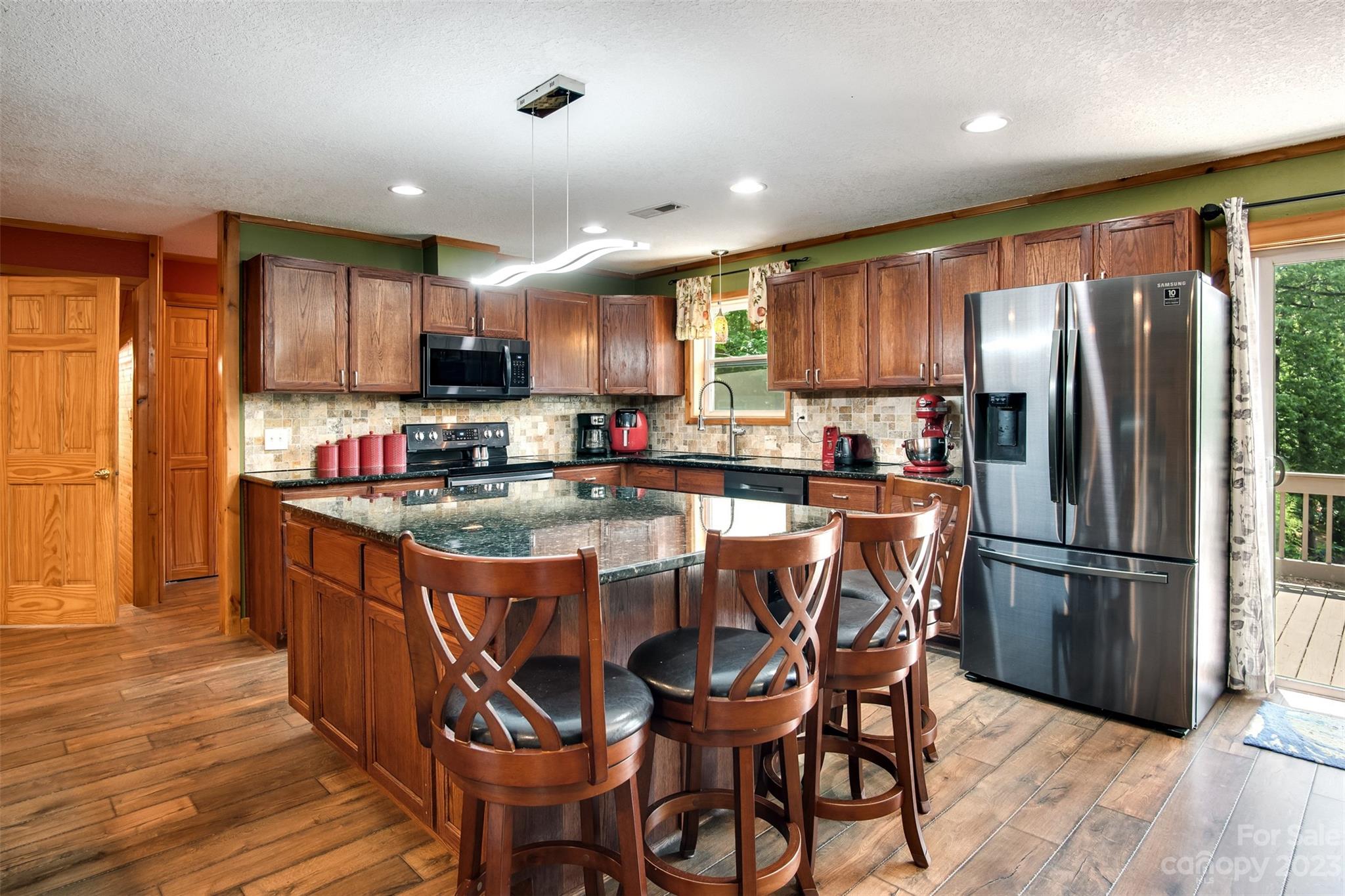669 Walker Point Road Hayesville, NC 28904 - Photo 3 of 46 a kitchen with stainless steel appliances granite countertop a stove top oven a refrigerator a sink and a dining table with wooden floor