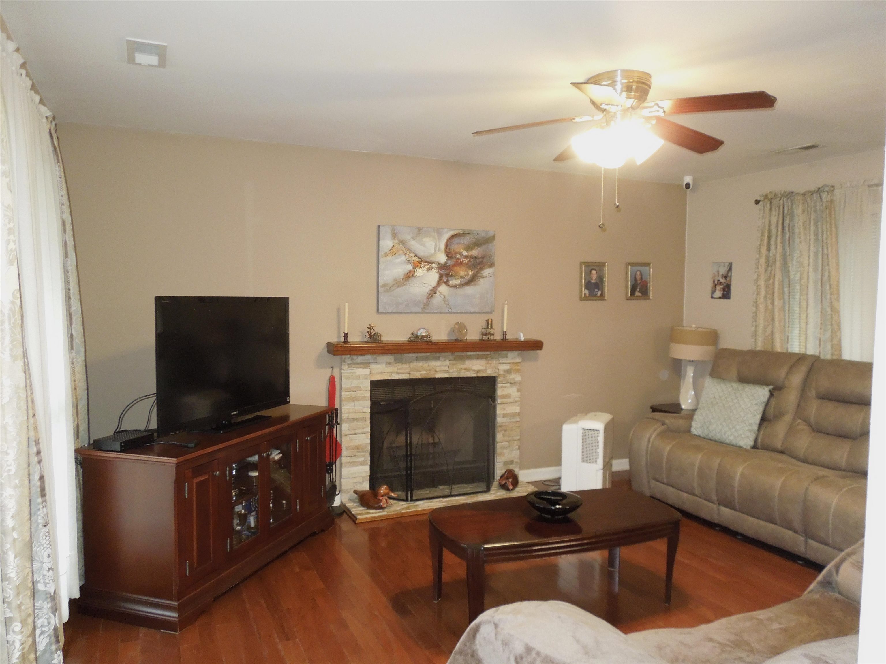 815 Willow Trace Myrtle Beach, SC 29572 - Photo 3 of 20 Living room with wood finished floors, a stone fireplace, and ceiling fan