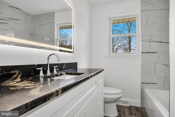 a bathroom with a granite countertop toilet sink and mirror