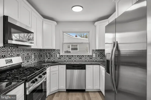 a kitchen with white cabinets and appliances