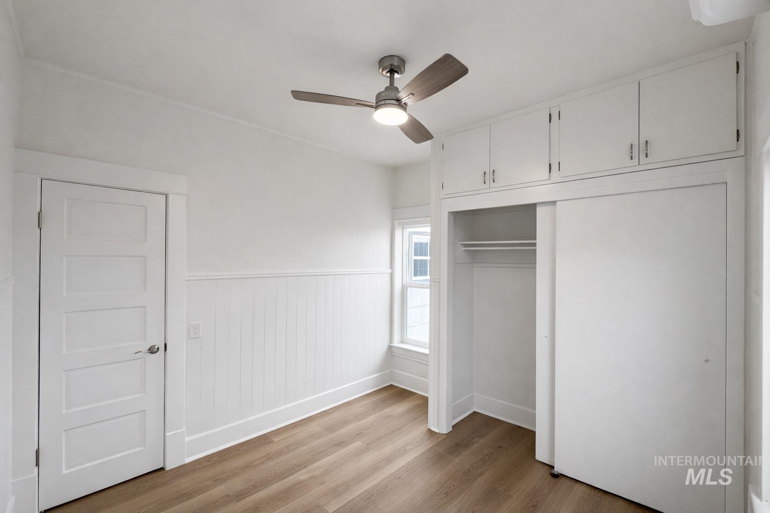 2 East Bates Avenue Parma, ID 83660 - Photo 3 of 7 Unfurnished bedroom featuring wainscoting, light wood-style flooring, a ceiling fan, and a closet