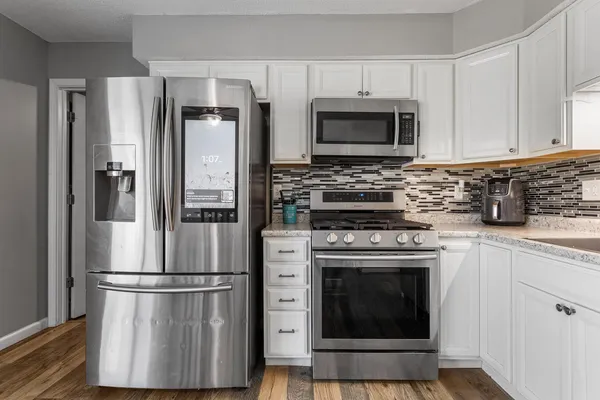 a kitchen with stainless steel appliances granite countertop a refrigerator a stove and a refrigerator