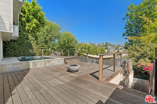 a view of a roof deck with table and chairs potted plants with wooden floor and fence