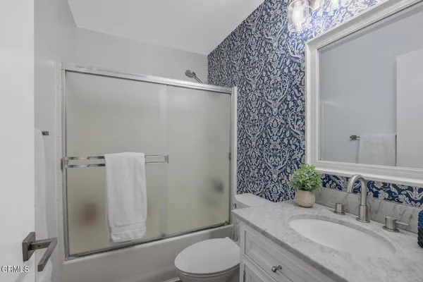 a bathroom with a granite countertop sink toilet and shower