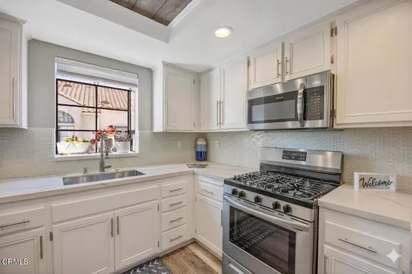 a kitchen with stainless steel appliances white cabinets granite counter tops and a window