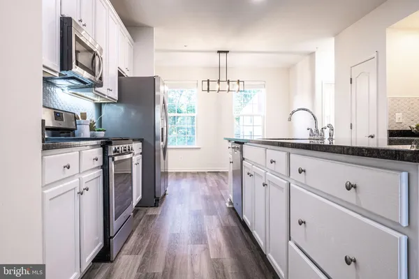 a kitchen with stainless steel appliances kitchen island granite countertop a sink stove refrigerator and cabinets