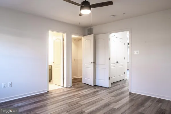 an empty room with wooden floor and a ceiling fan