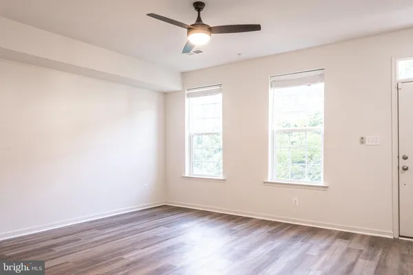 a view of an empty room with wooden floor and a window