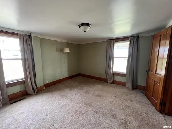 an empty room with windows and cabinet