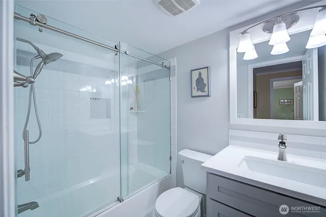 a bathroom with a shower sink vanity mirror and toilet