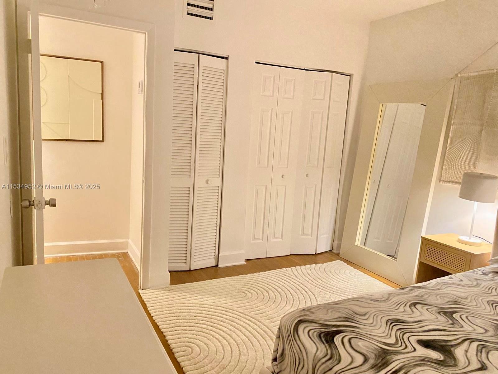 605 Euclid Avenue, Unit 103 Miami Beach, FL 33139 - Photo 5 of 8 a bedroom with a bed and a mirror