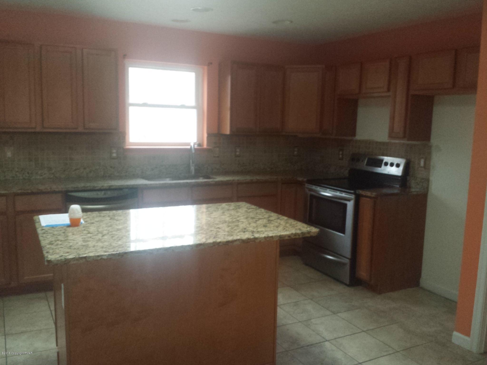 276 Powder Horn Road Henryville, PA 18332 - Photo 3 of 16 a kitchen with granite countertop a refrigerator a stove a microwave and wooden cabinets