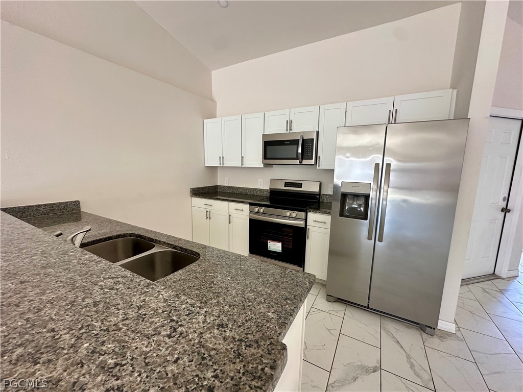 252 Southwest 3rd Street Cape Coral, FL 33991 - Photo 7 of 16 a kitchen with kitchen island a sink a refrigerator and a stove