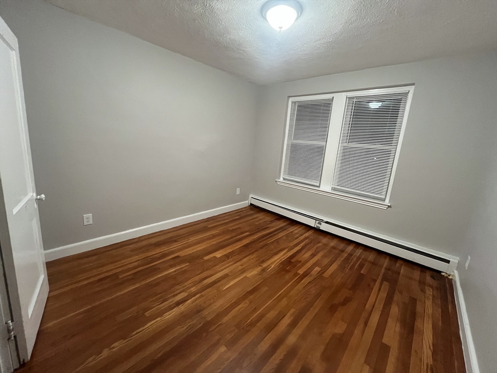 77 Green Street, Unit 24 Lynn, MA 01902 - Photo 4 of 5 an empty room with wooden floor and windows