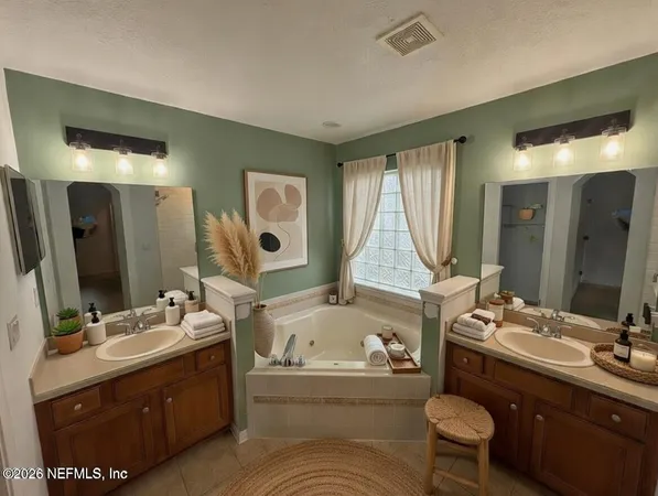 a bathroom with a tub double sink window and mirror