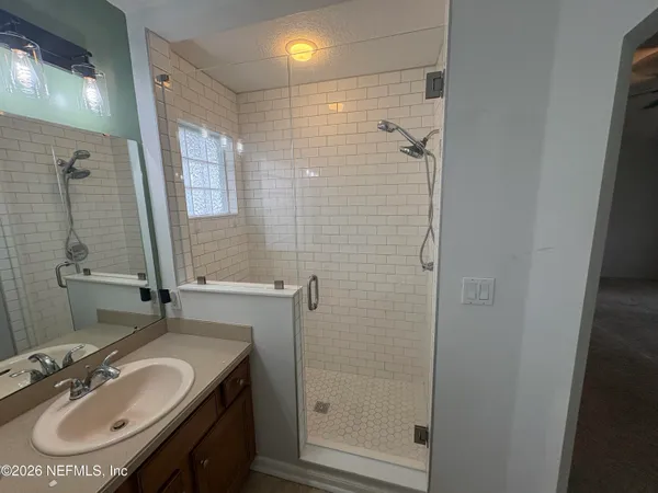 a bathroom with a sink shower and a mirror