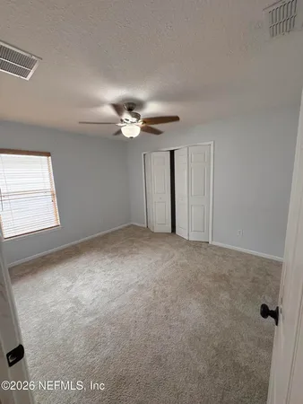 a view of an empty room with a chandelier fan