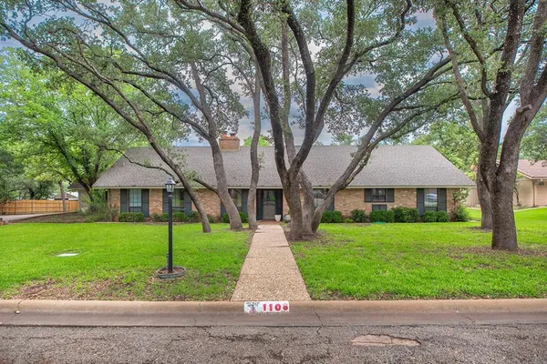 a front view of a house with a yard and trees