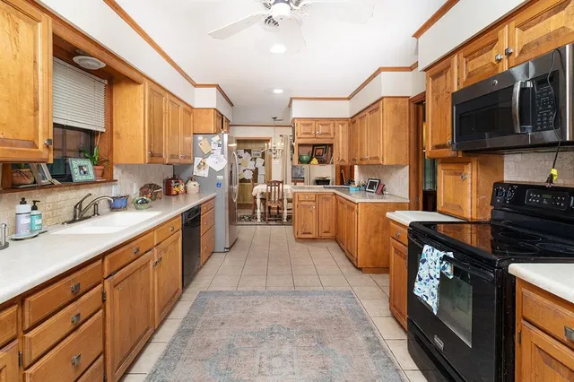 a large kitchen with stainless steel appliances granite countertop a stove top oven a sink dishwasher a dining table and chairs with wooden floor