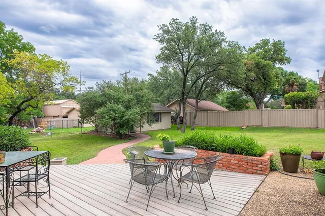 a view of a backyard with table and chairs potted plants and a palm tree