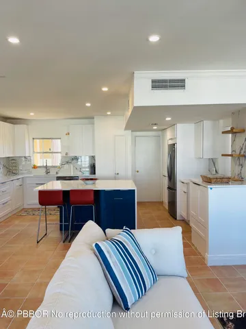 a large white kitchen with stainless steel appliances kitchen island granite countertop a table and chairs in it