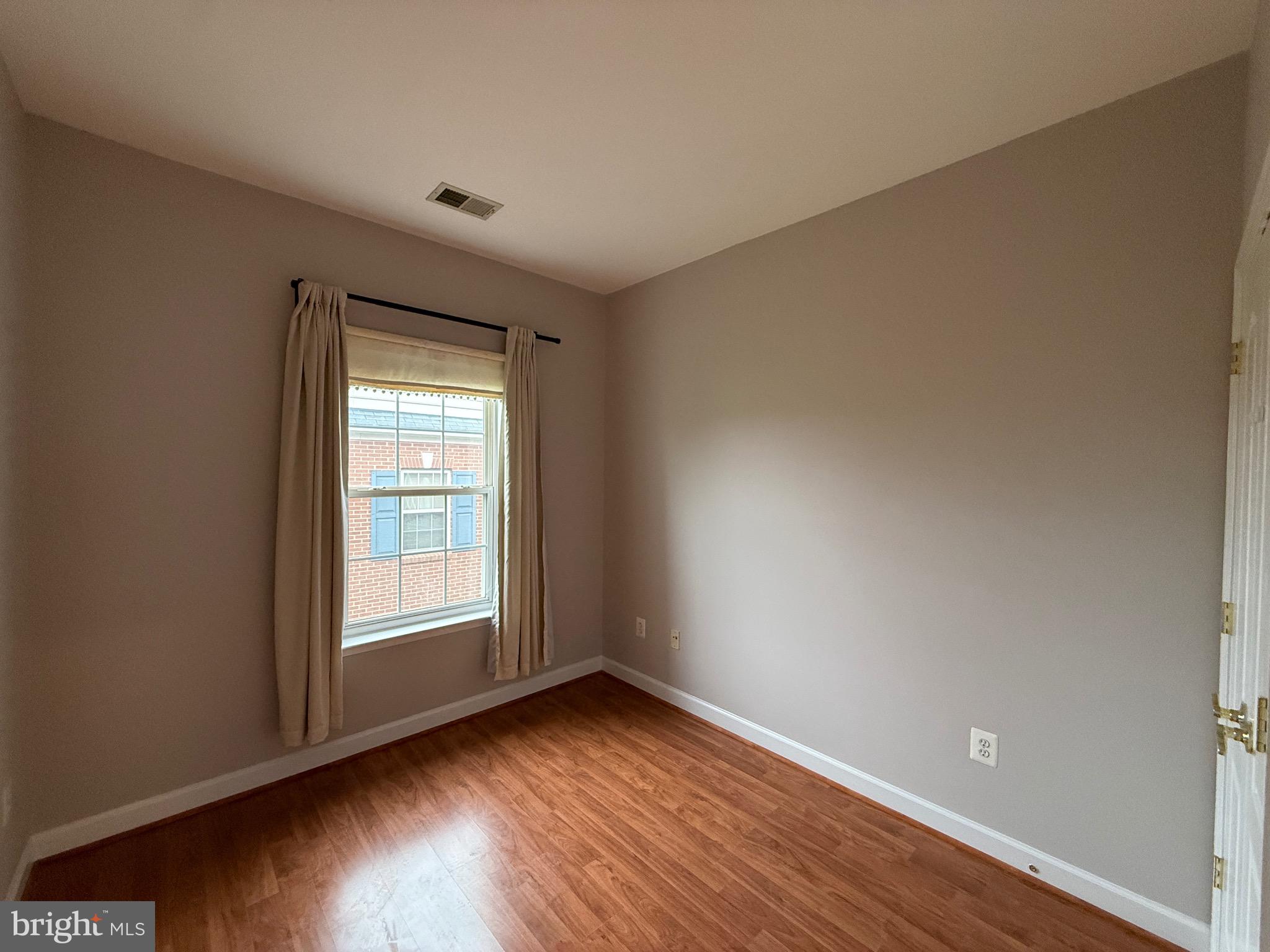 1127 Gaither Road Rockville, MD 20850 - Photo 23 of 26 an empty room with wooden floor and windows