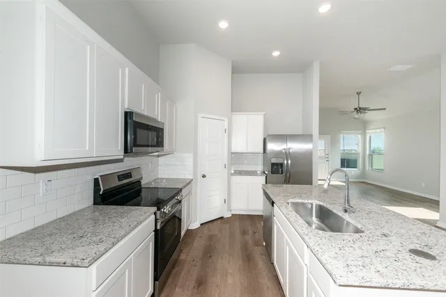 a kitchen with granite countertop a sink a counter top space stainless steel appliances and cabinets