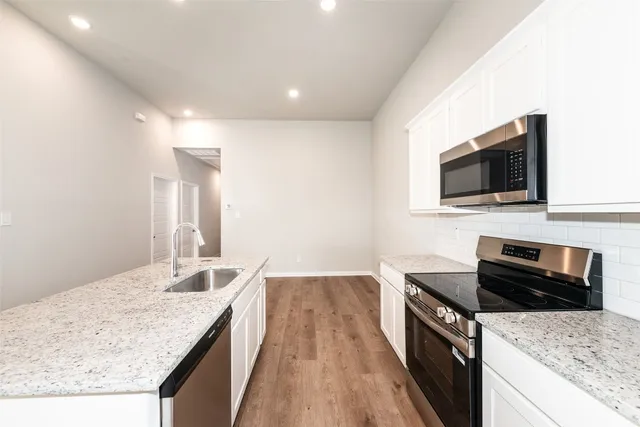 a kitchen with granite countertop a sink and a stove top oven with wooden floor