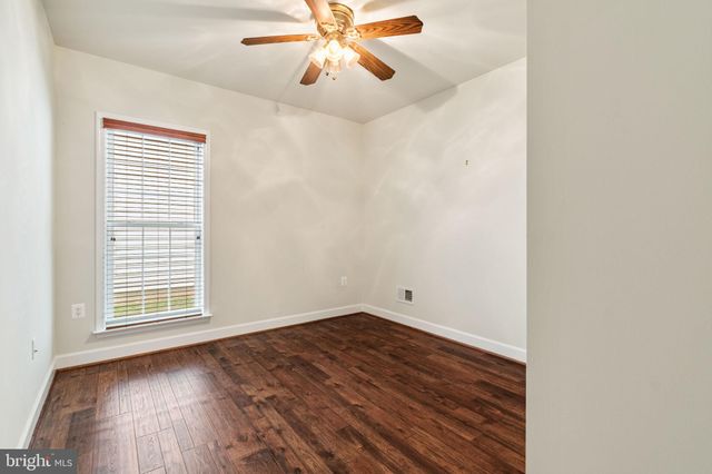 an empty room with wooden floor chandelier fan and windows