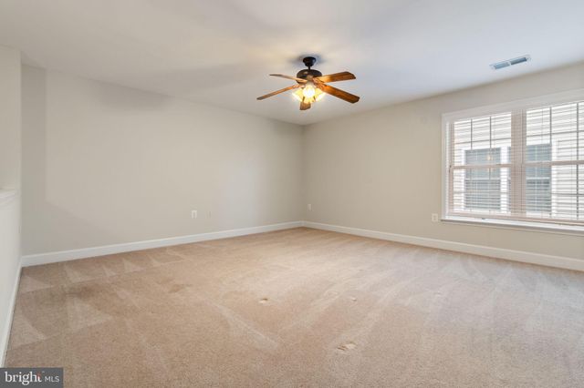 an empty room with windows and chandelier fan