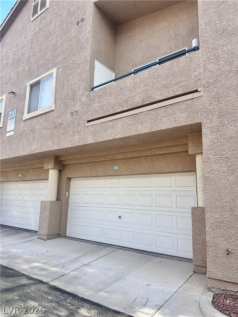 2053 Turquoise Ridge Street, Unit 202 Las Vegas, NV 89117 - Photo 17 of 18 Attached multi-car garages sit beneath upper-level balconies along the paved driveway.
