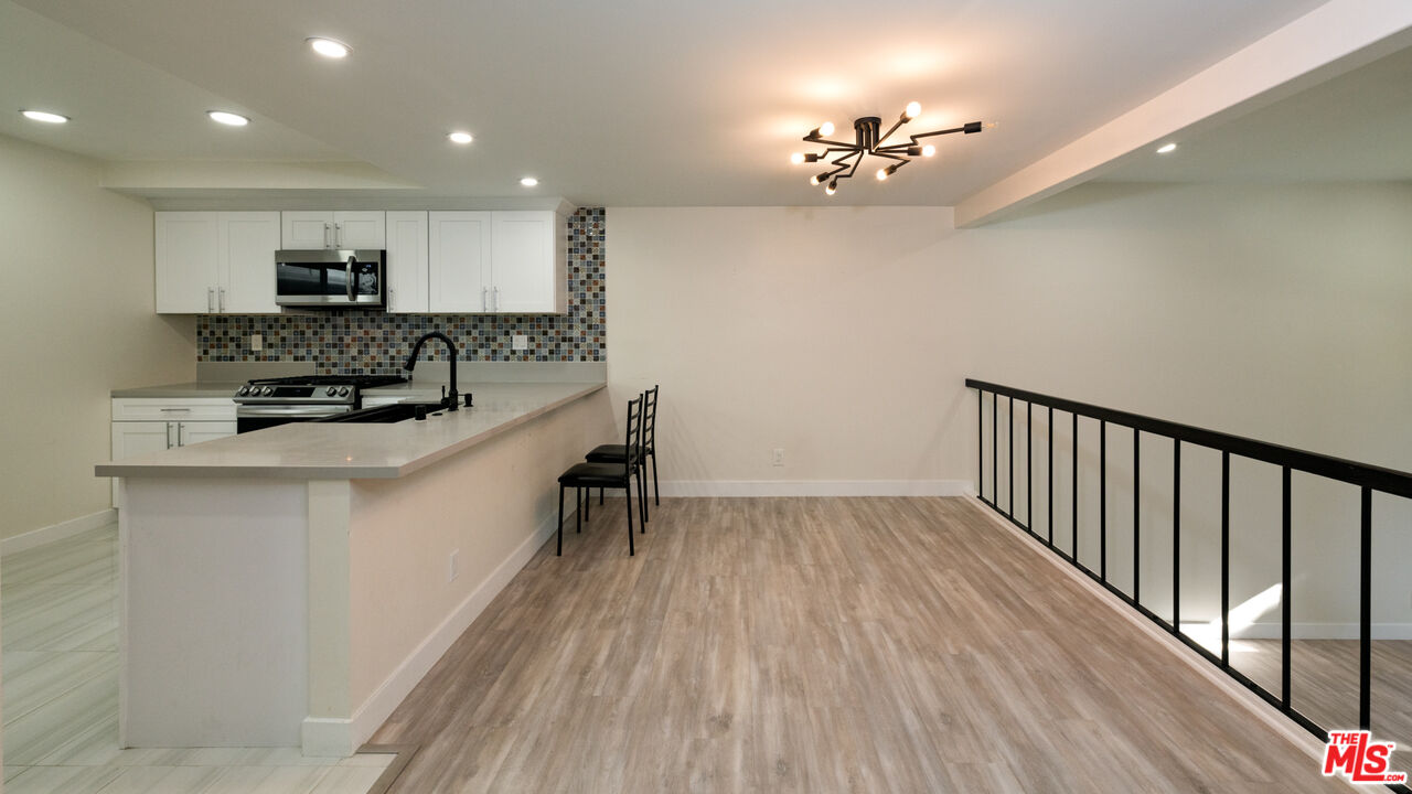 13206 Admiral Avenue, Unit F Marina del Rey, CA 90292 - Photo 5 of 21 a kitchen with kitchen island a sink and a stove top oven with wooden floor