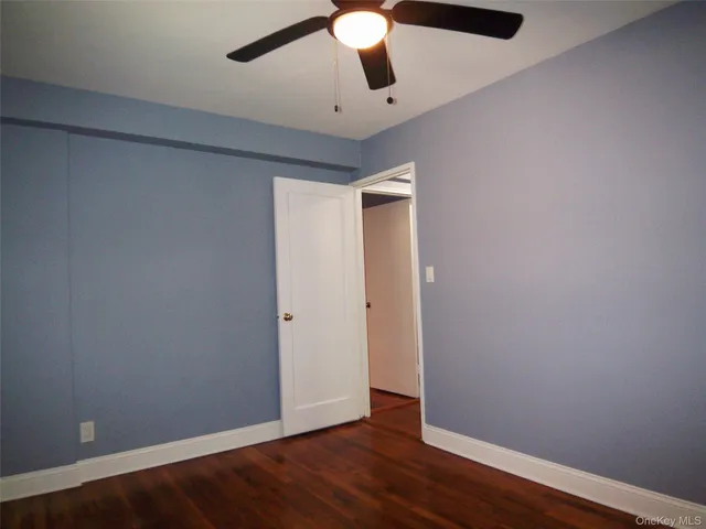 an empty room with wooden floor fan and window