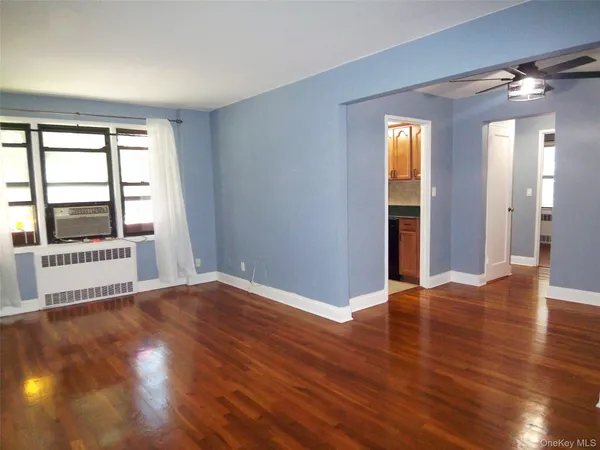 a view of an empty room with glass door and wooden floor