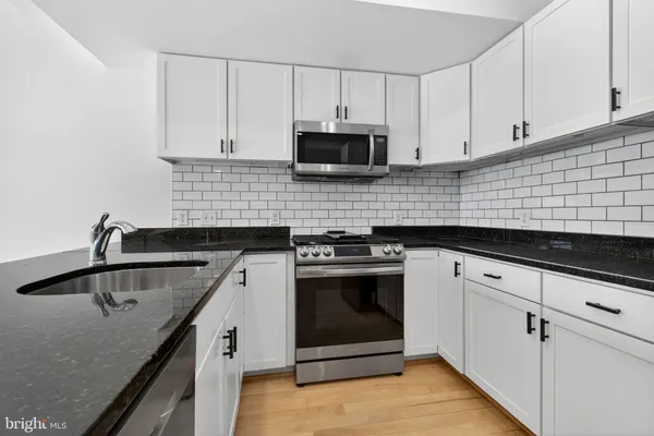 a kitchen with granite countertop a sink stove and cabinets