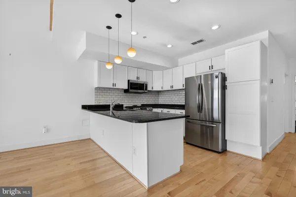 a kitchen with granite countertop a refrigerator and a stove top oven
