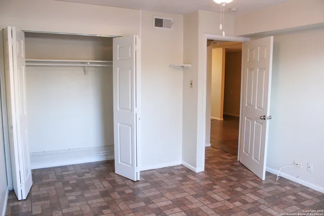 an empty room with a chandelier fan and windows