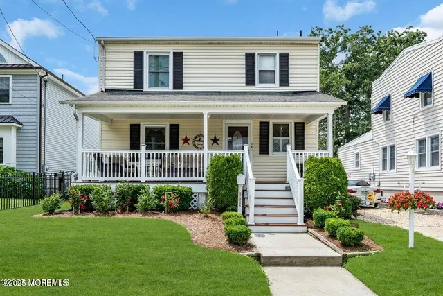 a view of a house with brick walls and a yard with plants and large trees