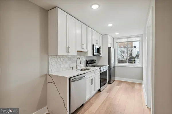a kitchen that has a lot of white cabinets and wooden floor