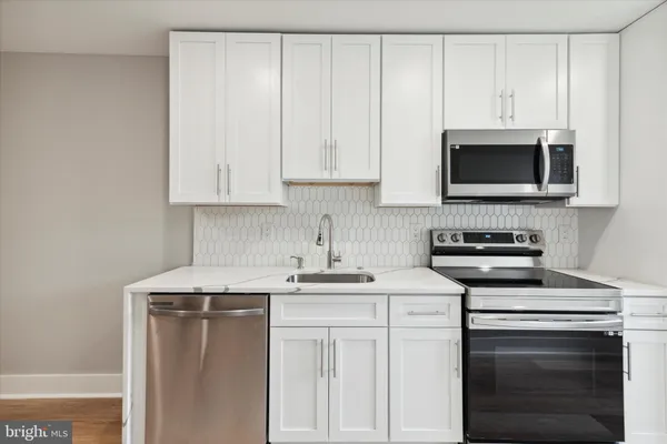 a kitchen with granite countertop white cabinets and stainless steel appliances
