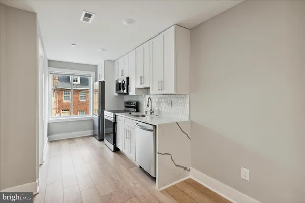 a kitchen with a refrigerator a stove top oven and white cabinets