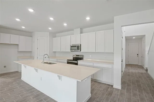 a kitchen with a sink a stove a refrigerator and white cabinets with wooden floor