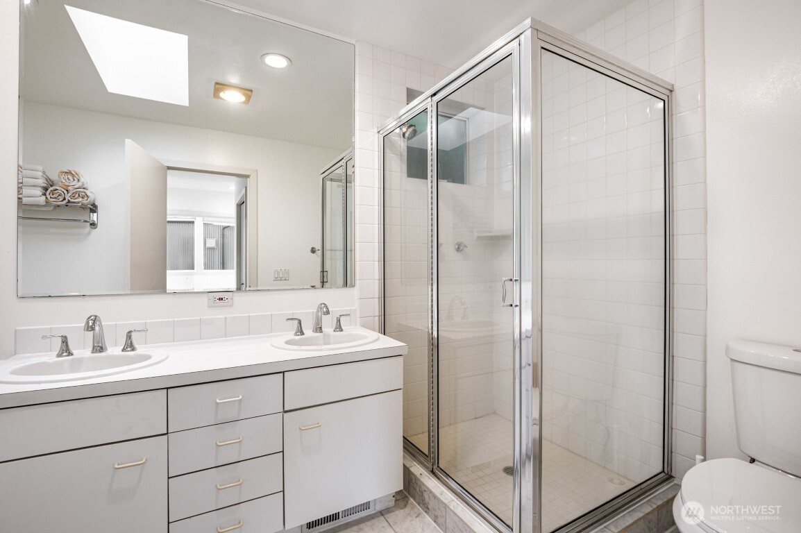 2216 19th Avenue East Seattle, WA 98112 - Photo 19 of 23 a bathroom with a shower sink vanity and mirror
