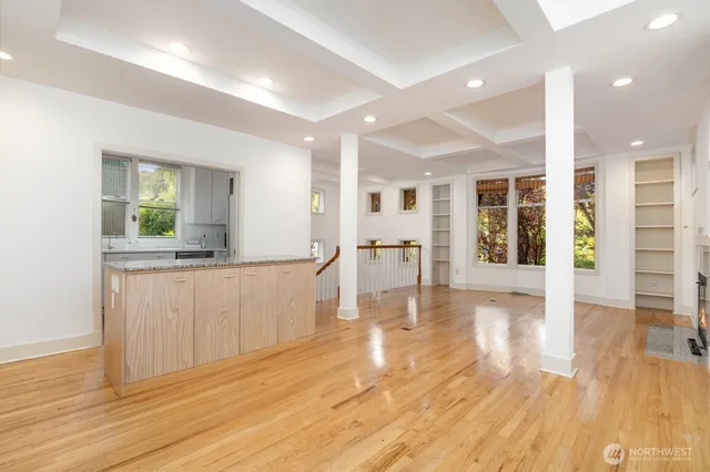 an empty room with wooden floor and entrance to other room