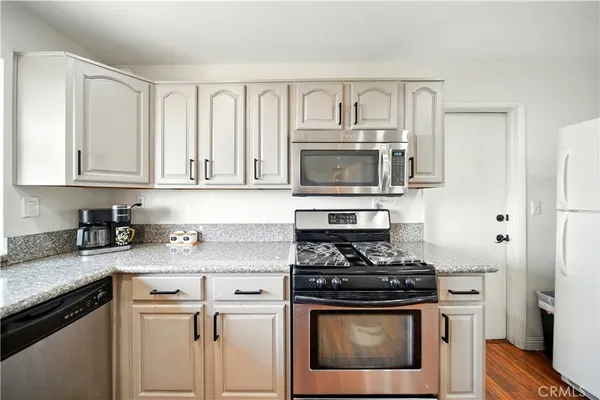 a kitchen with granite countertop a stove sink and microwave
